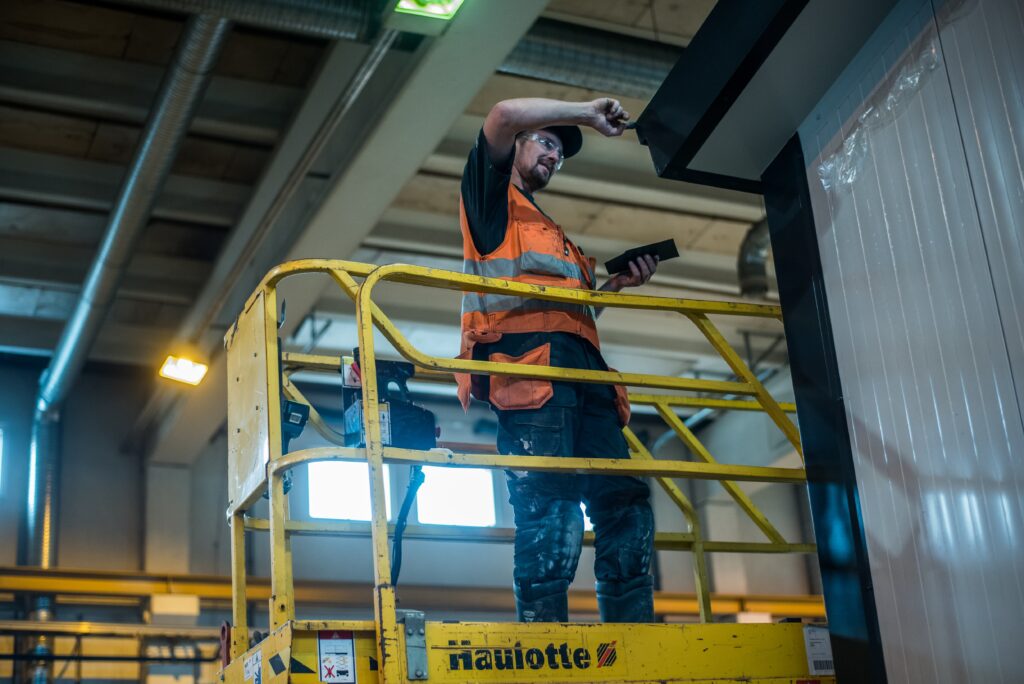 Työntekijä teollisuusnostimen korissa